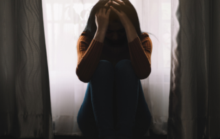 A person sitting alone in a dimly lit room, symbolizing the isolation caused by mental health stigma in South Africa."