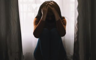 A person sitting alone in a dimly lit room, symbolizing the isolation caused by mental health stigma in South Africa."