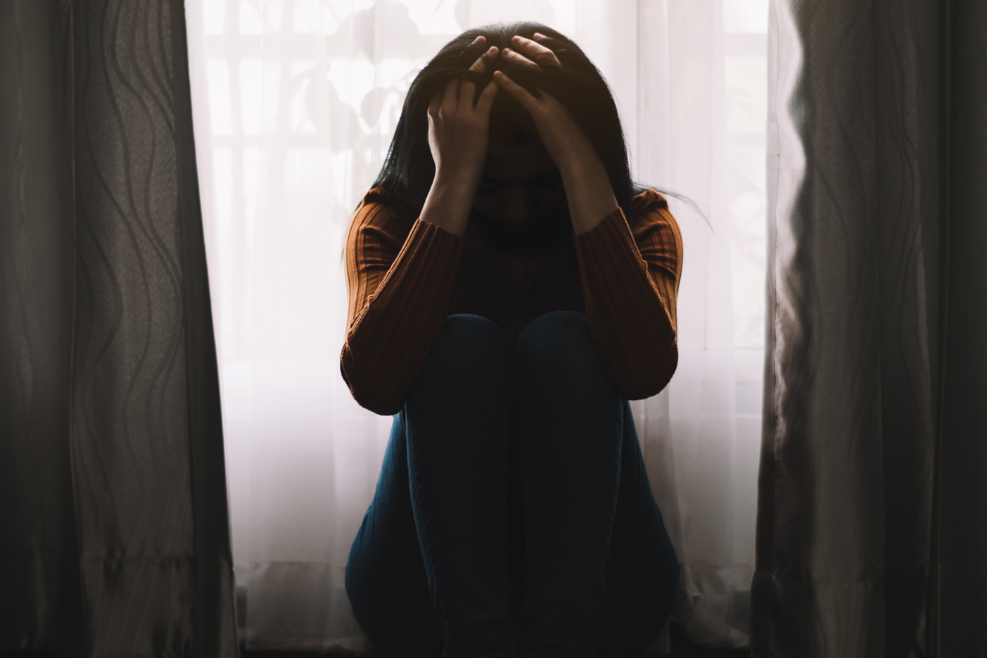 A person sitting alone in a dimly lit room, symbolizing the isolation caused by mental health stigma in South Africa."