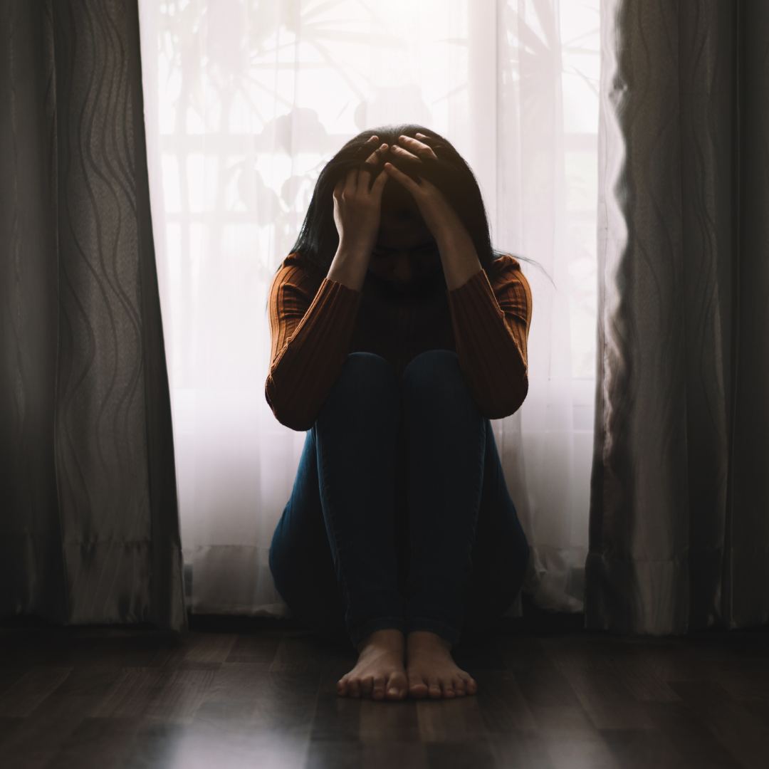 A person sitting alone in a dimly lit room, symbolizing the isolation caused by mental health stigma in South Africa."