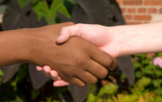 Two individuals from diverse cultural backgrounds shaking hands, symbolizing mutual understanding and collaboration in cross-cultural counselling.