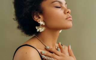 A serene woman with her hands on her chest, head tilted back, and eyes closed, exuding a sense of calm and mindfulness.