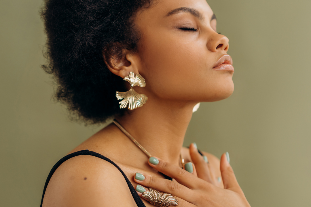 A serene woman with her hands on her chest, head tilted back, and eyes closed, exuding a sense of calm and mindfulness.